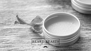 A tin of Beard Beasts beard balm on a textured wooden surface, suggesting a step in the 'how to use beard balm' process for effective men's grooming.