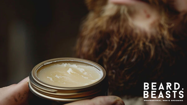 Close-up of a tin of mustache wax, highlighting its texture, with a blurred background featuring a beard—perfect for comparing mustache wax vs beard balm.