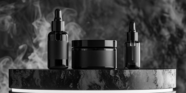 omparing beard oil vs beard balm with a black dropper bottle of beard oil and a sleek tin of beard balm on a dark background.