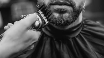 Close-up of a beard being shaped with precision using a beard trimmer equipped with a guard for an even and styled look.