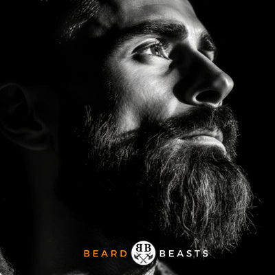 Dramatic black and white profile image of a man with a round face featuring a full, thick beard, gazing upwards thoughtfully, highlighted against a dark background with the 'Beard Beasts' logo prominently displayed.