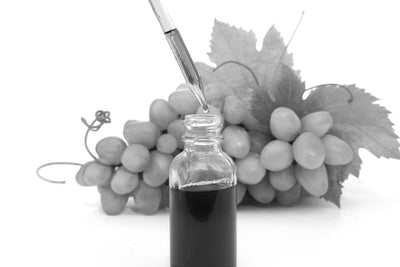 Dropper bottle with grapeseed oil and fresh grape bunch in the background, highlighting natural ingredients for beard care.