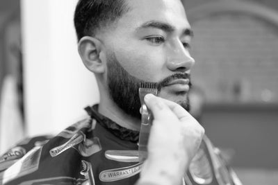 Stylish man getting his beard dyed at a barber shop, featured image for beard dyeing article.