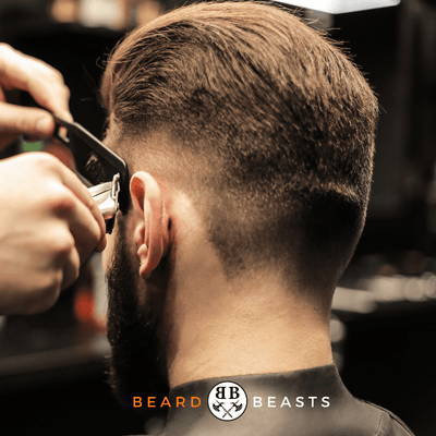 Barber carefully trimming a man's hair to create a slick back hairstyle with a clean fade. Logo of Beard Beasts displayed, indicating professional grooming services for men. Featured image for the article 'How To Get A Slick Back Hairstyle For Men'.