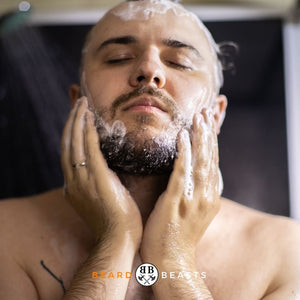 A man with closed eyes, enjoying the sensation of washing his beard with conditioner, featured on the article "How to Use Beard Conditioner". The logo of Beard Beasts is visible at the bottom of the image