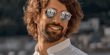 Man with trendy medium-length curly haircut wearing sunglasses and smiling, showcasing stylish curly haircuts for men in 2024. The relaxed, natural curls highlight the versatility and character of curly hairstyles.