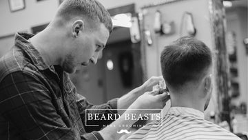 Barber giving a client a taper fade haircut in a salon, representing a tutorial on how to ask for a taper fade.
