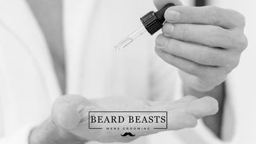 A man's hands dispensing beard oil from a dropper, illustrating how to use beard oil.