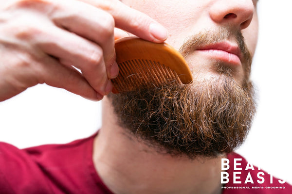 Close-up of a man using a wooden comb to remove beard knots, demonstrating proper techniques on how to detangle your beard for smooth and manageable facial hair.