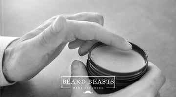 A black and white photo showing a hand delicately scooping out pomade from an open container. The image suggests a comparison or choice between oil-based versus water-based pomade for styling.
