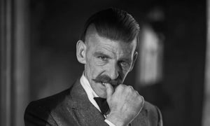 Arthur Shelby haircut featuring a disconnected undercut with slicked-back top and shaved sides, styled with vintage Peaky Blinders flair.