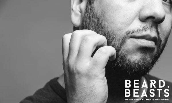 Close-up of man scratching his patchy beard during the awkward beard phase