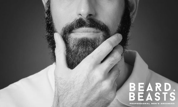 Close-up of a well-groomed bearded man touching his beard, representing the results of consistent beard maintenance and expert grooming care.