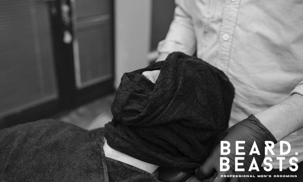 Man receiving a hot towel shave at a barbershop—classic grooming ritual showing the benefits of a hot towel shave for men.