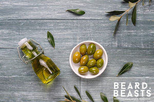 Olive oil for beard care with fresh olives and a glass bottle.
