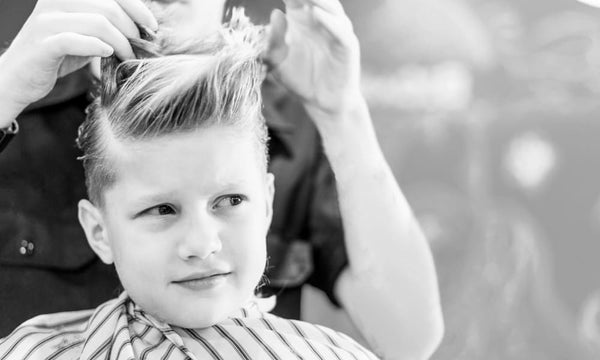 A young boy with thick hair getting a stylish haircut at the barbershop, perfect for managing volume and maintaining shape.