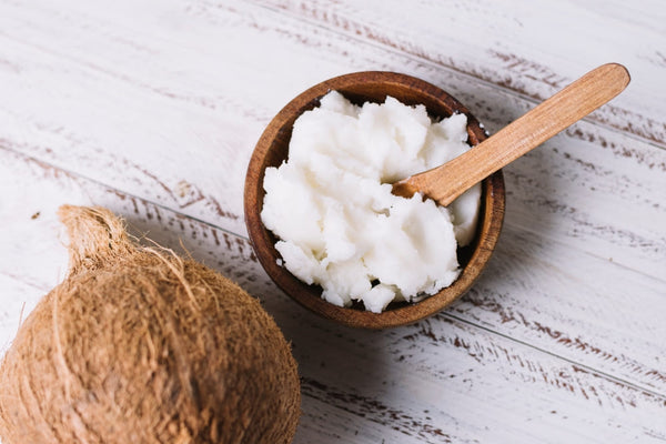 A bowl of coconut butter alongside a whole coconut, ideal for natural beard care.