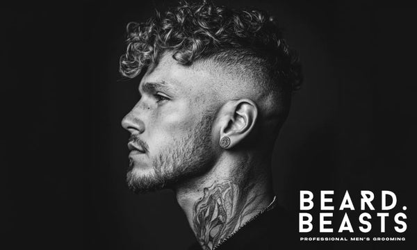 Side profile of a man with a curly undercut hairstyle, featuring defined curls on top and a high skin fade, set against a dark background.