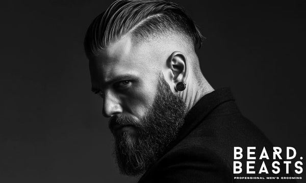 Bearded man with a disconnected slick back hairstyle, featuring a defined hard part, high fade, and polished top—modern grooming style in black and white.