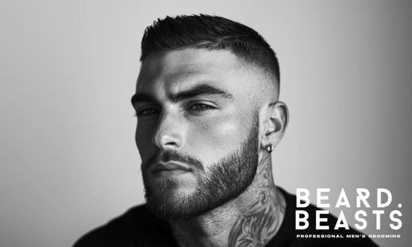 Black and white portrait of a man with a short fade and defined beard, showcasing one of the best men’s summer haircuts for a cool, clean look.