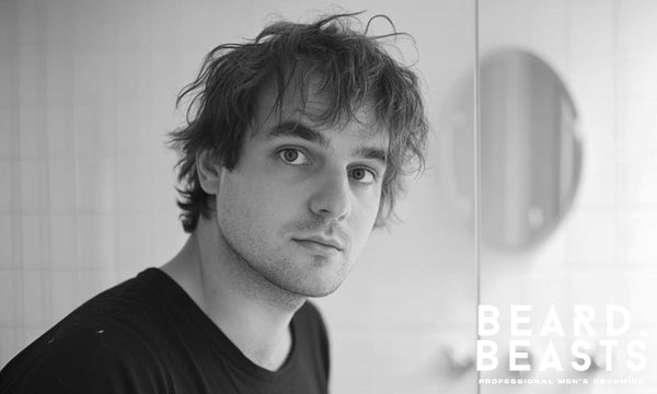 Man in his 30s with flat, unstyled hair looking in the mirror—representing the struggle with flat hair in men.