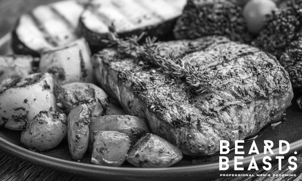 Grilled steak, roasted vegetables, and leafy greens on a plate—nutrient-rich foods for beard growth.