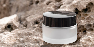 Modern jar of hair wax on a rock surface. Frosted glass jar with black lid, ideal for achieving a natural, textured look. Perfect for various hair types and lengths, highlighting the benefits of hair gel vs wax in hair styling products