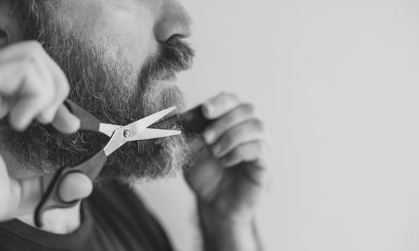 Man trimming his beard with scissors and a comb—featured image for a step-by-step guide on how to trim a beard with scissors.