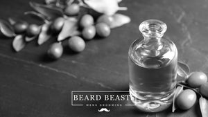 Clear bottle of jojoba oil for beard conditioning with scattered jojoba seeds and leaves on a dark slate background