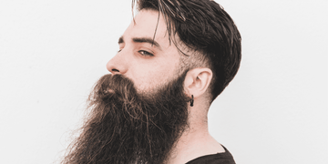 Man with a low fade haircut and long, full beard, featuring a stylish combination of neatly faded sides and back with a voluminous top and well-groomed beard, showcasing a bold and modern look for 2024.
