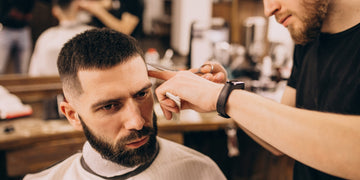 A man getting a low fade haircut, pondering if the low fade is better than the high fade