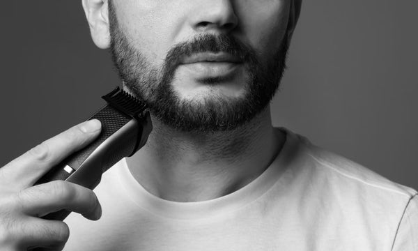 Close-up of a man using an electric beard grooming tool to trim his facial hair, demonstrating precise beard maintenance and shaping.
