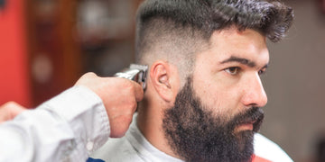 Man getting a fade haircut at a barber shop, showcasing the fade vs taper comparison.