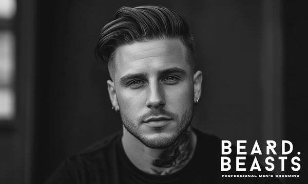 A black-and-white portrait of a man with a high volume comb over undercut, featuring a textured, swept-back top and cleanly faded sides.
