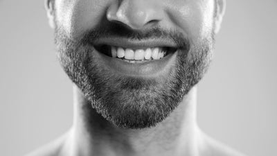 Man smiling with a six-week beard in a black and white close-up photograph