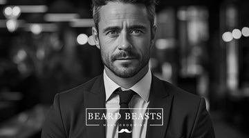 A sophisticated man with an 8mm beard, wearing a suit and tie, exudes confidence and elegance in a monochromatic setting, representing Beard Beasts Men's Grooming.