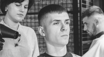 Man receiving a crew cut hairstyle at a barbershop, reflecting the crew cut vs buzz cut debate