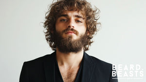 Side profile of a man with a full curly beard and voluminous curly hair, highlighting a natural and rugged grooming style.