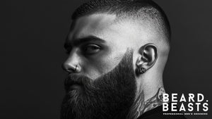 Profile of a man with a sharp fade haircut and a long, thick, well-groomed beard, highlighting the contrast between the closely cropped hair and the full beard. 