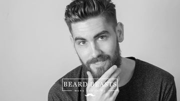 A man with a groomed beard and stylish haircut, exemplifying a look that falls in the debate of drop fade vs mid fade