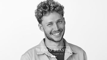 A cheerful man with naturally curly hair, showcasing a trendy hairstyle as part of a men's grooming concept by 