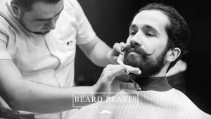 A professional barber meticulously trims and styles a man's medium beard in a barbershop, capturing the essence of sophisticated men's grooming with medium beard styles.