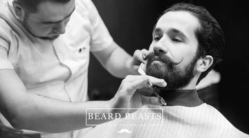 A professional barber meticulously trims and styles a man's medium beard in a barbershop, capturing the essence of sophisticated men's grooming with medium beard styles.