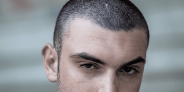 Close-up of a man with a number 3 buzz cut, highlighting the even 3/8 inch (10 mm) length that provides a clean and neat appearance.