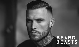 A black and white portrait of a stylish man with an oblong face shape, featuring a well-groomed Short Boxed Beard, one of the best beard styles for oblong faces. 