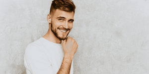 Smiling man with a stylish fade haircut, featuring short sides and a longer, textured top. The haircut showcases a modern and trendy look, perfect for men seeking popular fade haircuts for men.