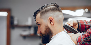 Man getting a classic undercut with a high fade at the barber. Learn how to ask for an undercut to achieve this stylish look.