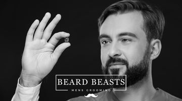 A monochrome image of a man with a well-groomed beard holding up a small capsule, with an interest in what vitamins help beard growth.